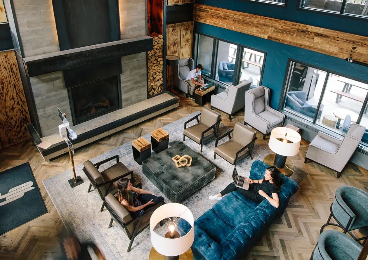 Overhead view of the Gravity Haus Breckenridge common lounge with sofas, armchairs and a tall fireplace.