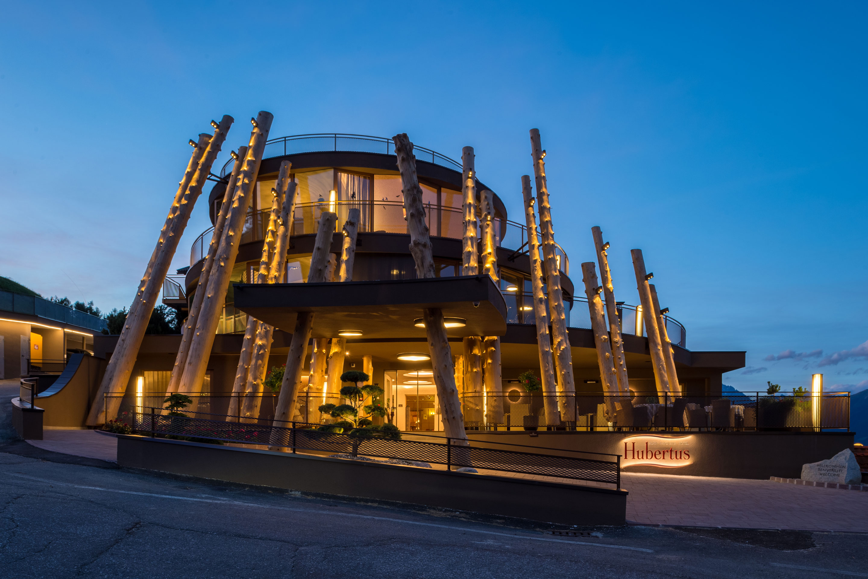 Modern timber-clad hotel exterior at dusk at Alpin Panorama Hotel Hubertus, Olang, Italy