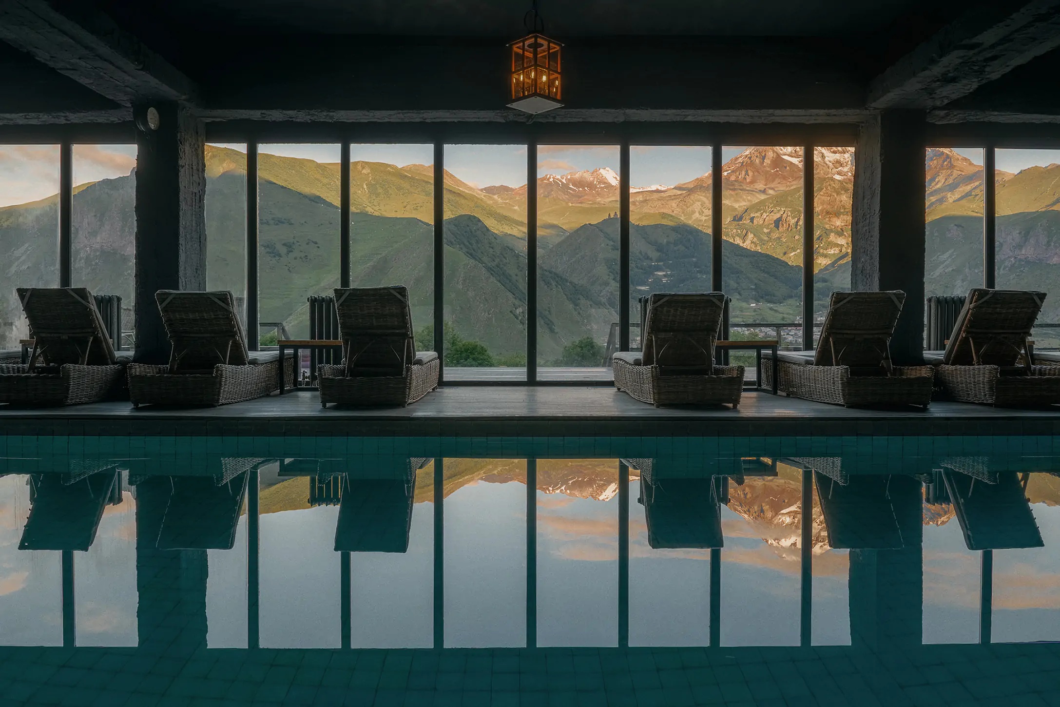 Indoor swimming pool with loungers facing windows overlooking mountains at Rooms Hotel Kazbegi, Georgia