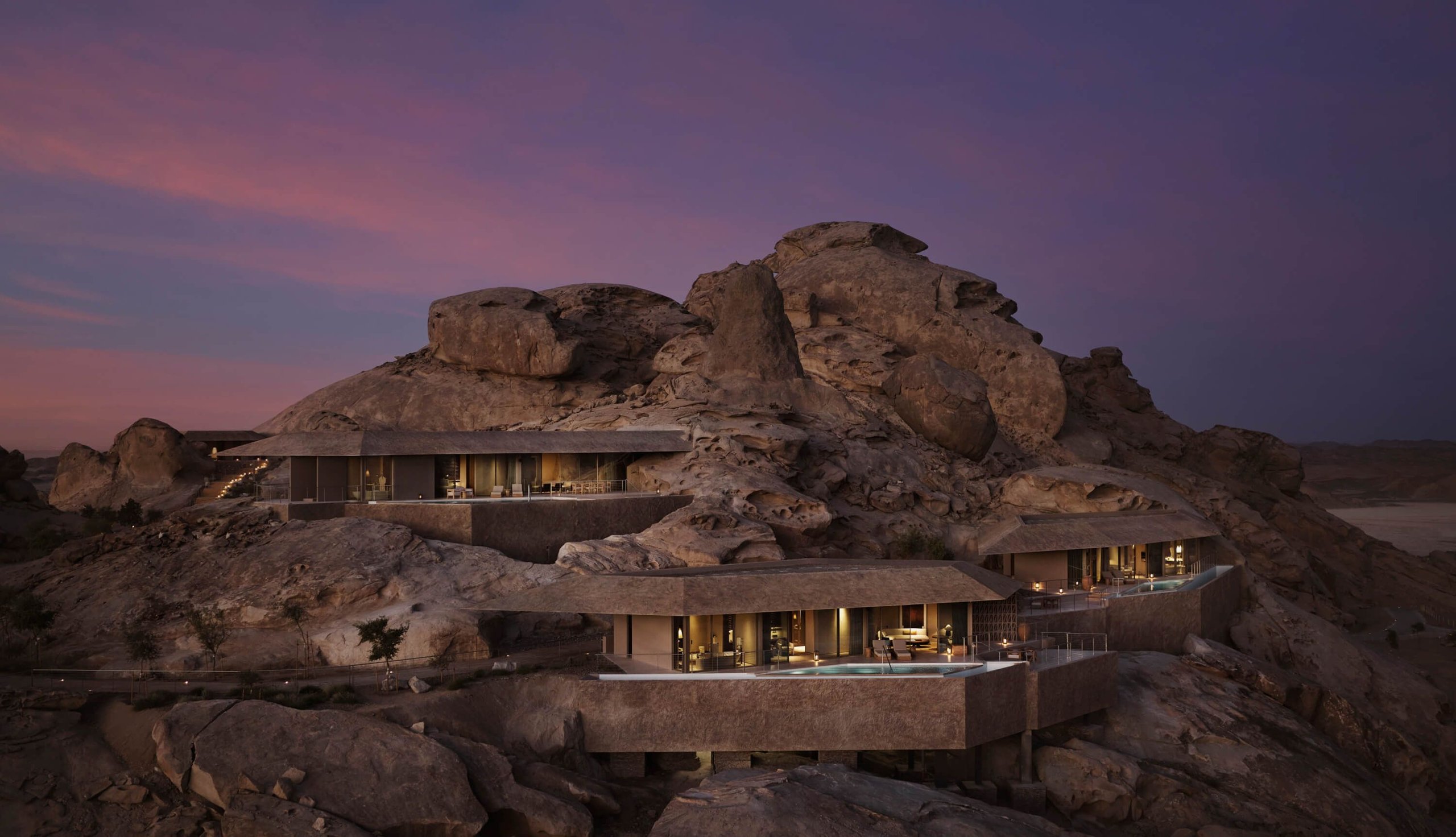 Villas at Desert Rock terraced into the granite massif at dusk, each with its own pool