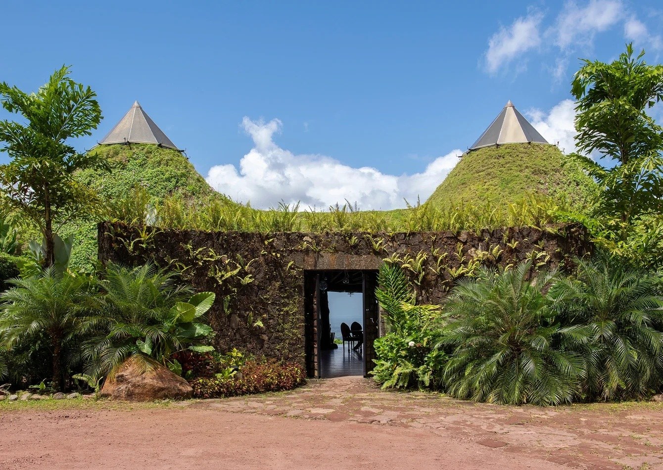 Living green roof and conical roof peaks above a lodge entrance at Origins Floral, Origins Luxury Lodge