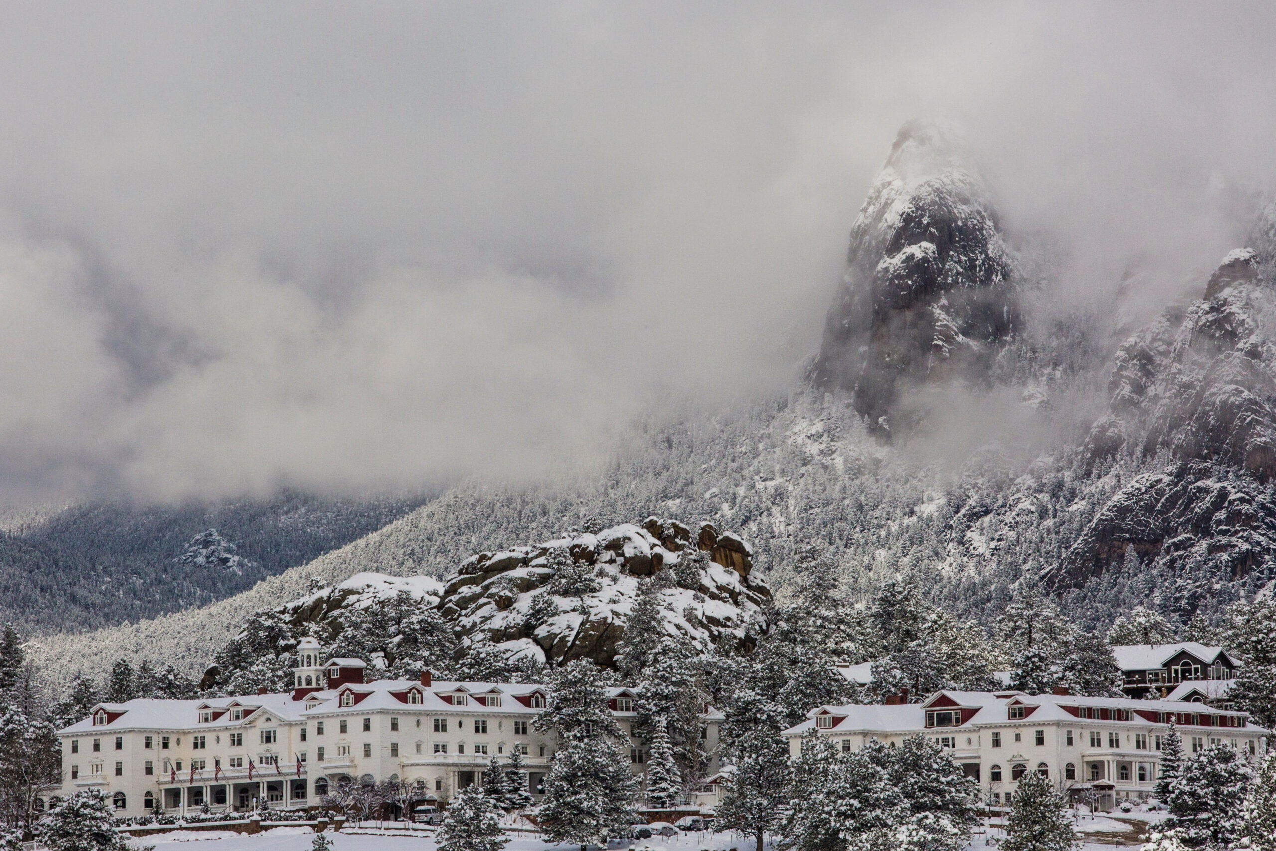 Hotel in snow below misty rocky mountains at The Stanley Hotel, Estes Park, USA