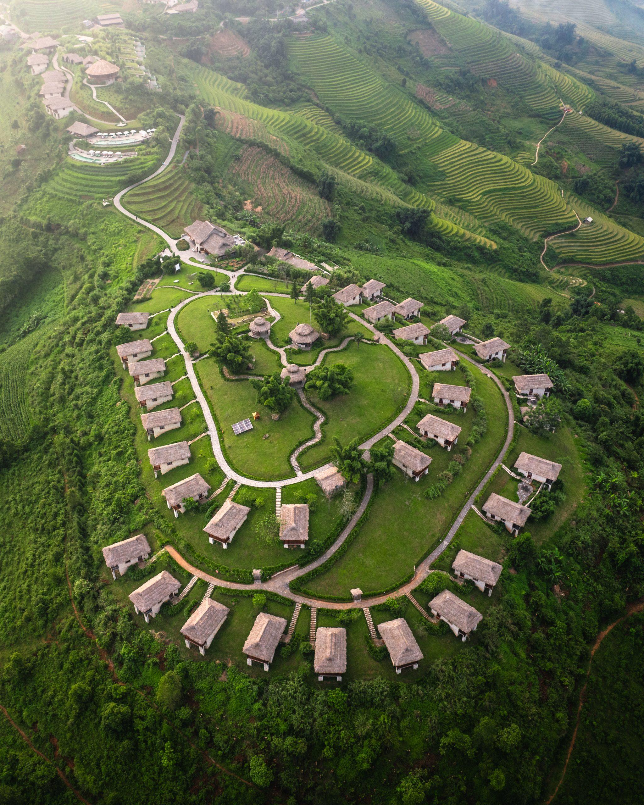 Overhead view of stone cottages arranged along a green hilltop, Topas Ecolodge, Sapa, Vietnam