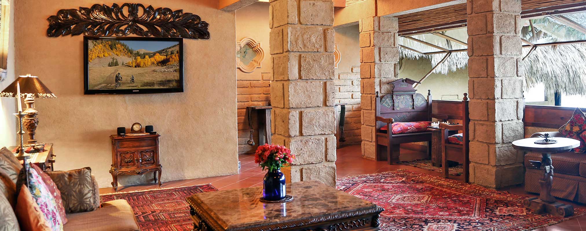 Rustic lounge with carved wooden chairs and a stone fireplace, Laguna Lodge, Lake Atitlán, Guatemala
