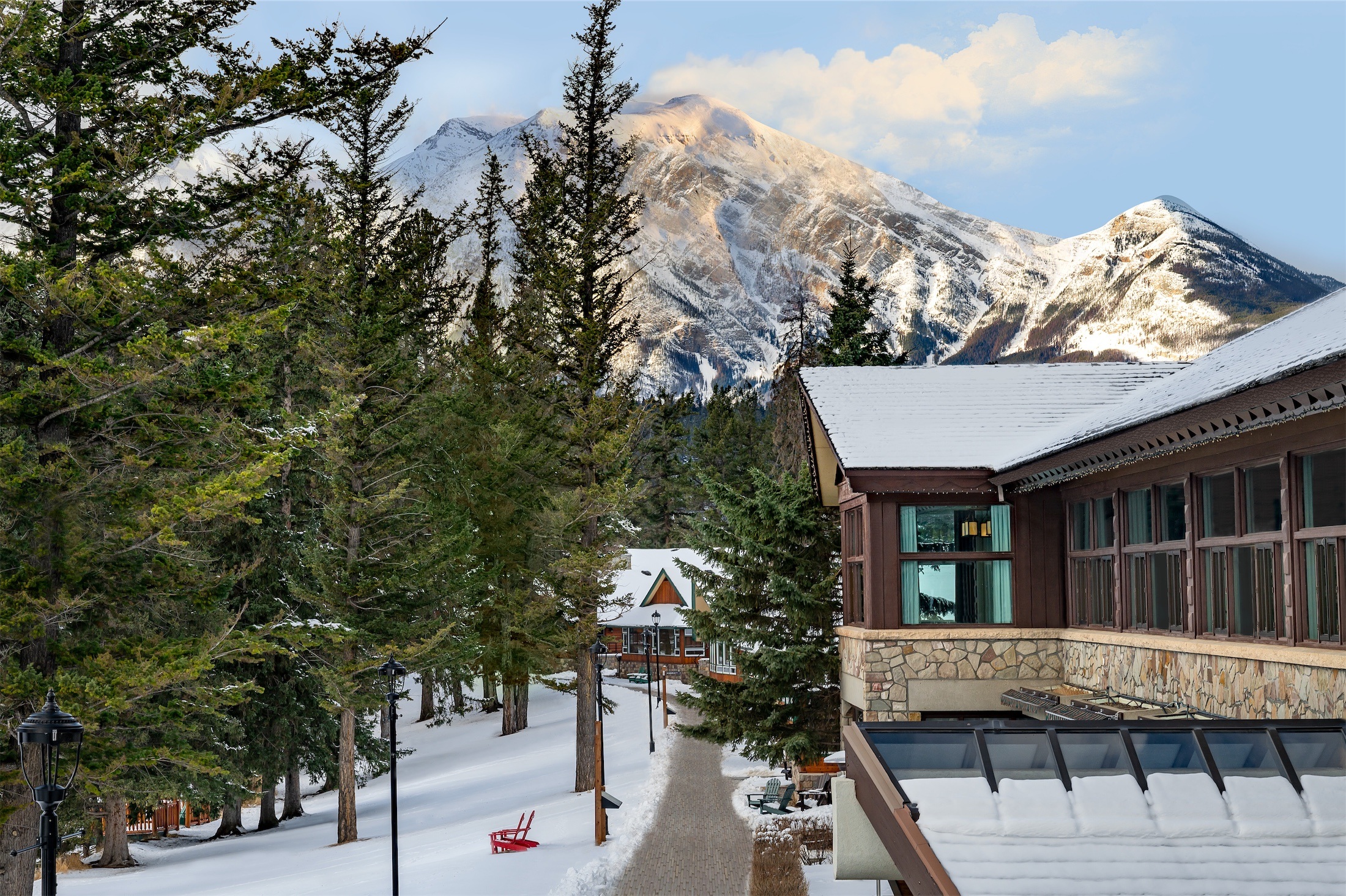 Snow-covered lodge exterior with mountains beyond at Fairmont Jasper Park Lodge, Jasper, Canada