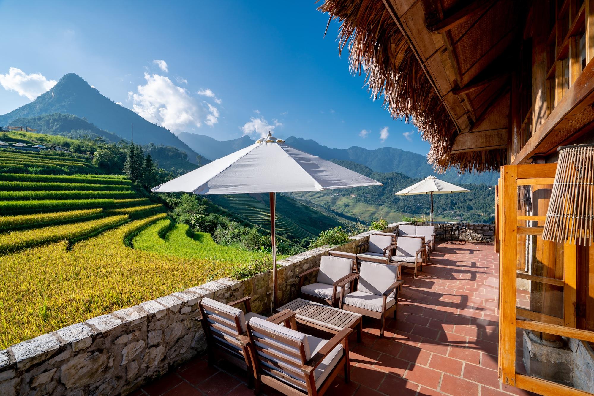 Terrace lounge chairs overlooking rice terraces and a mountain peak, Topas Ecolodge, Sapa, Vietnam