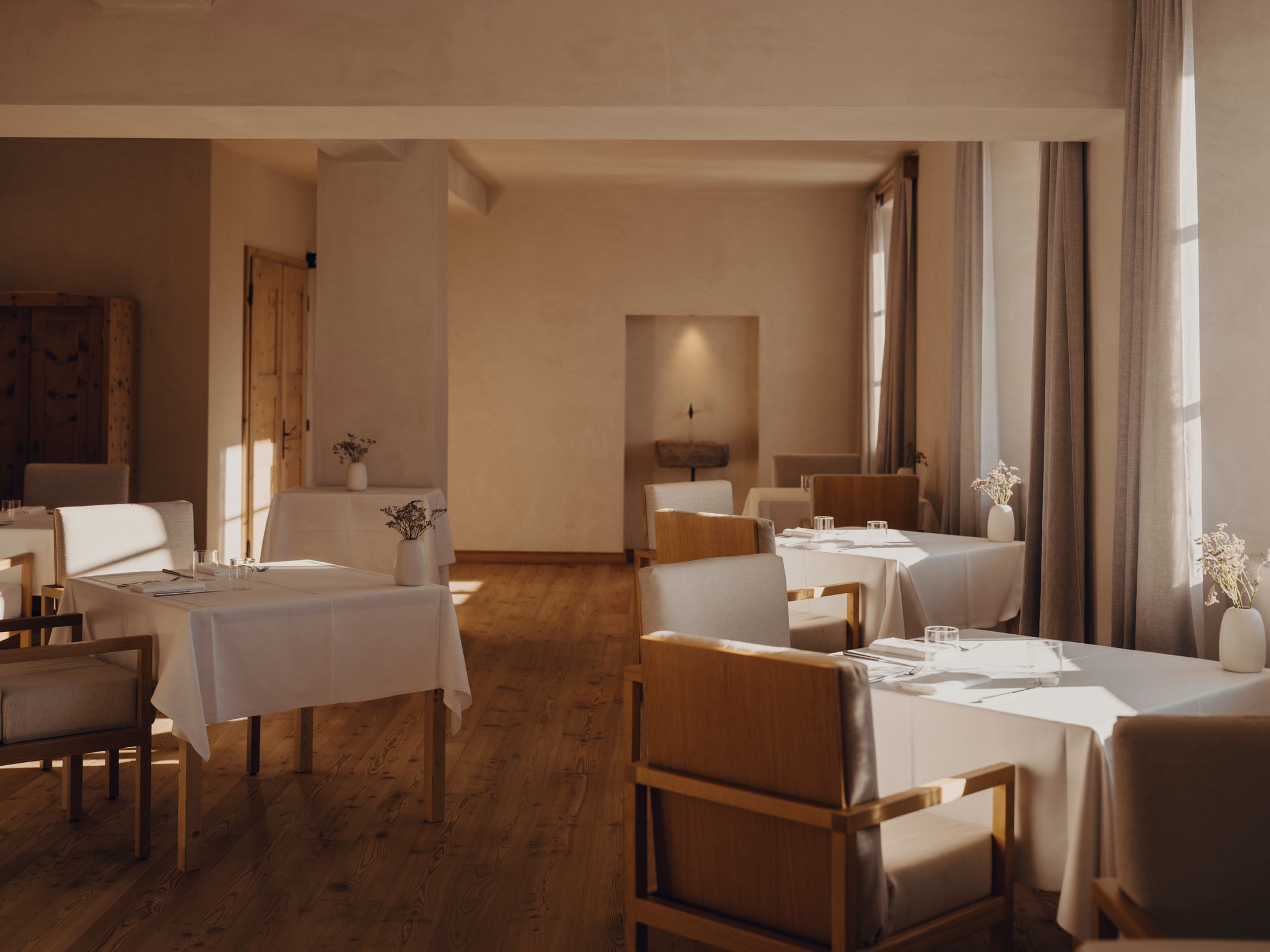 A spacious FORESTIS suite sitting room with a sofa, dining area, and large windows, Dolomites, Italy