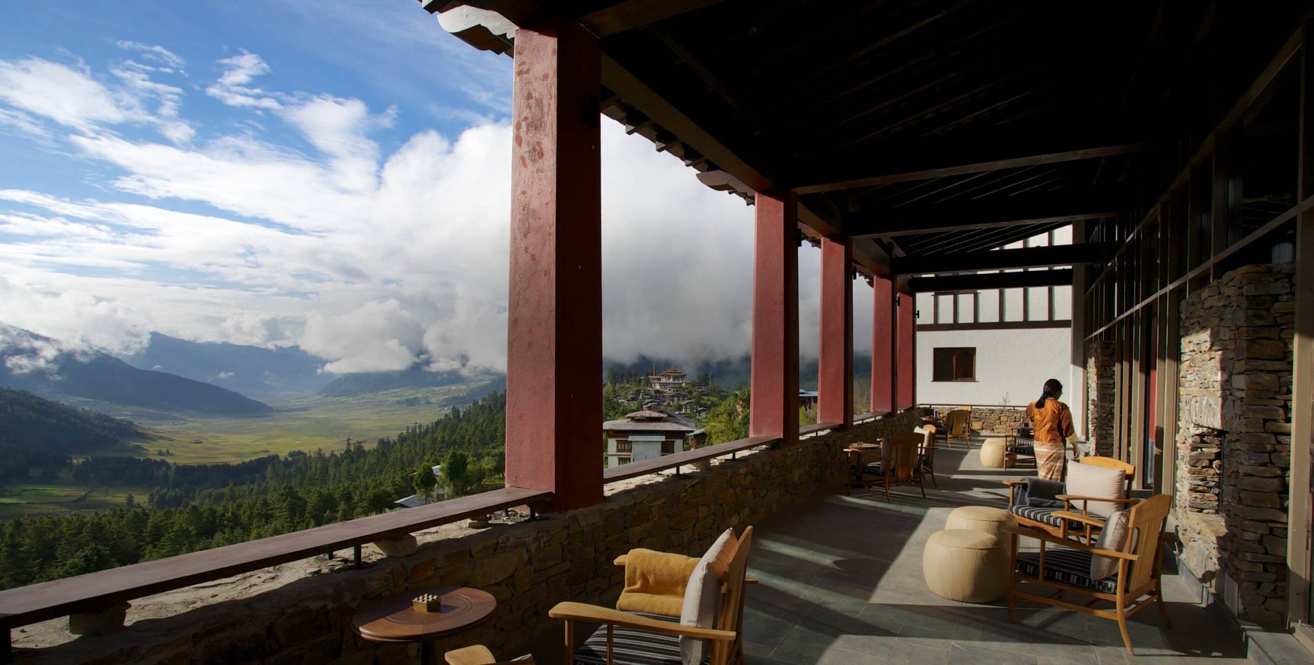 Covered terrace at Gangtey Lodge with stone walls and timber pillars overlooking the broad Phobjikha Valley