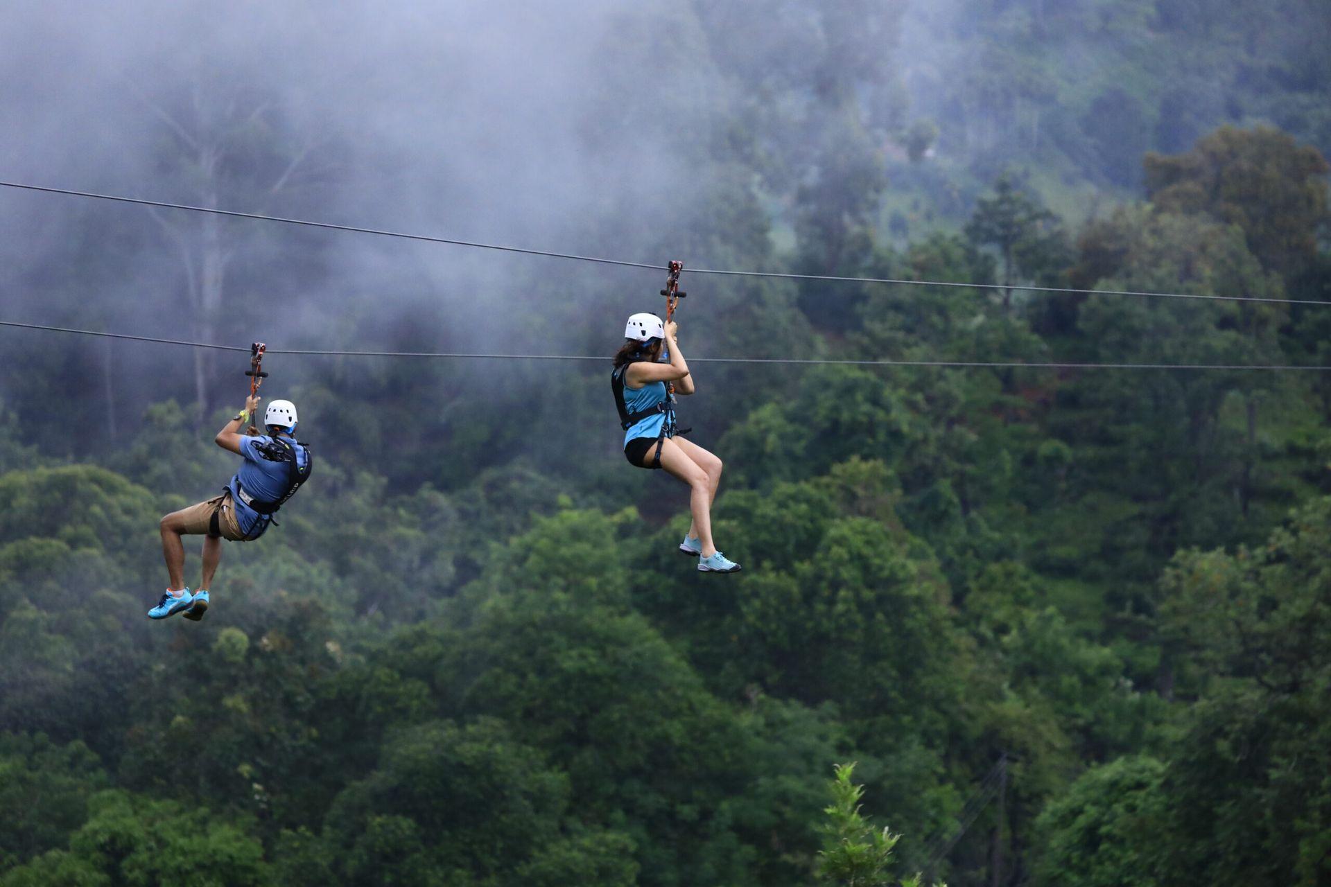 Two guests ziplining above a misty forest at Flying Ravana Adventure Park, 98 Acres Resort, Ella, Sri Lanka