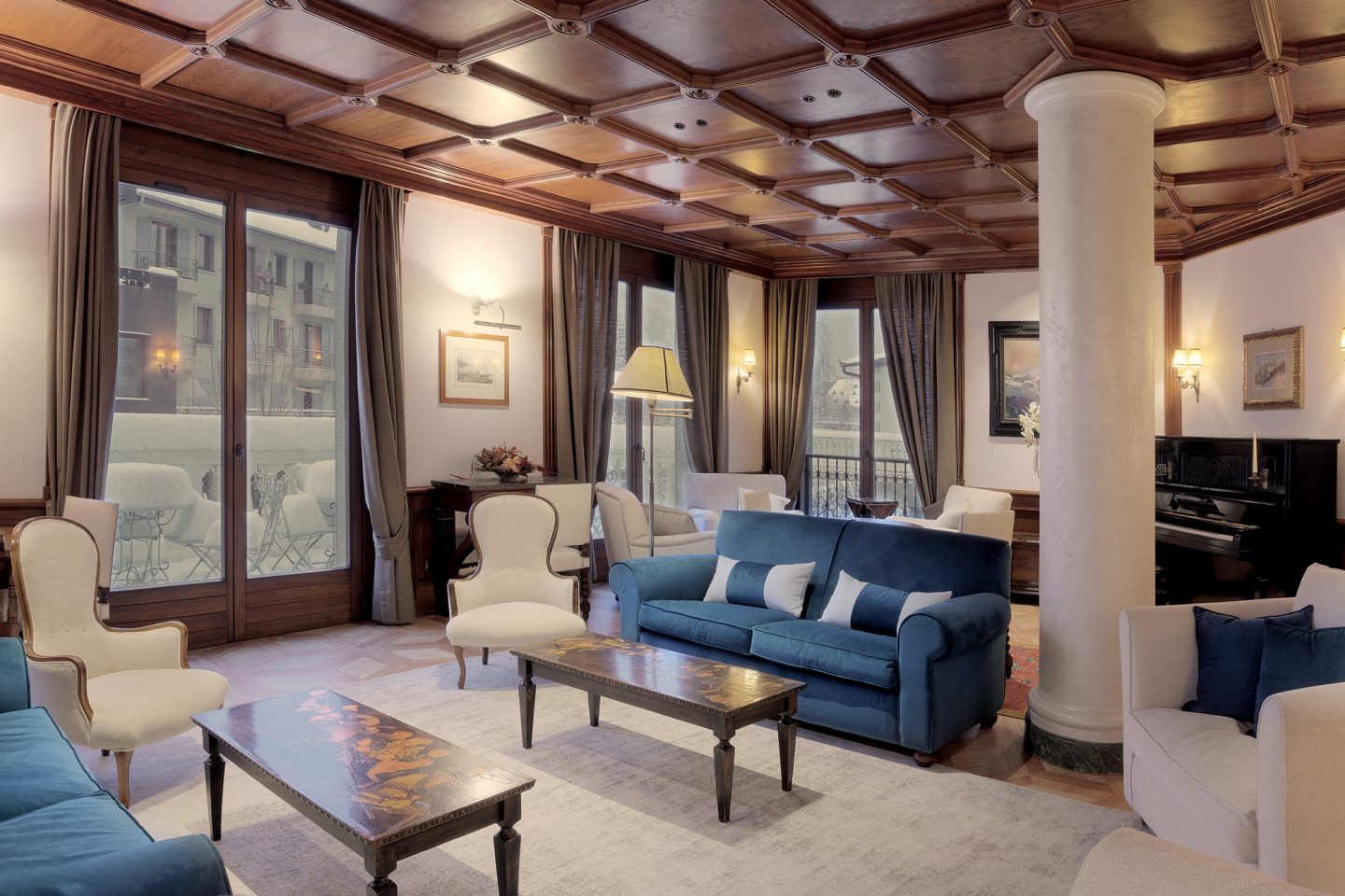 Blue velvet sofas, carved timber ceiling and piano in the hotel lounge, Grand Hôtel des Alpes, Chamonix, France