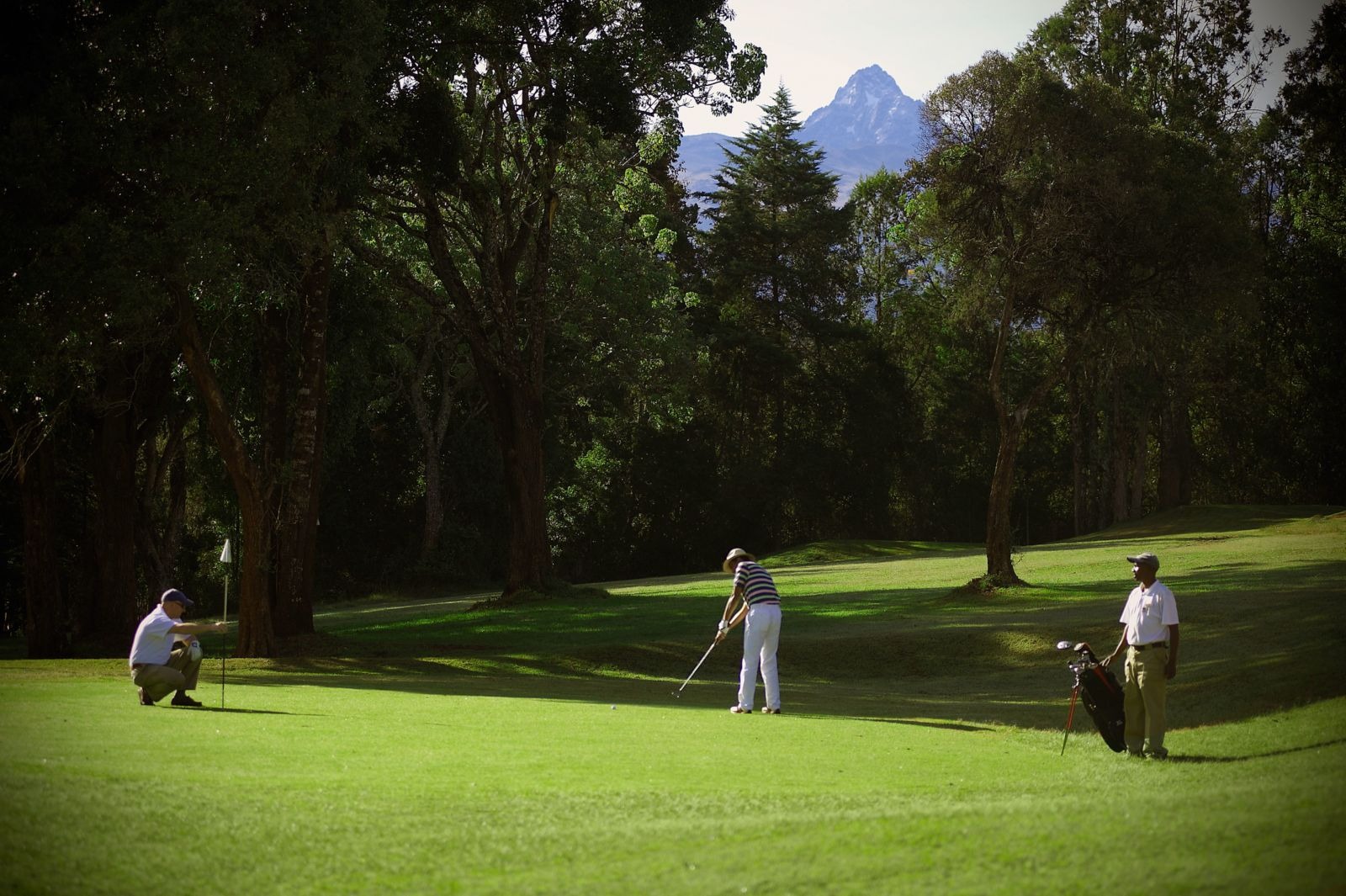 Golfers on a green with a distant mountain view, Fairmont Mount Kenya Safari Club, Nanyuki, Kenya