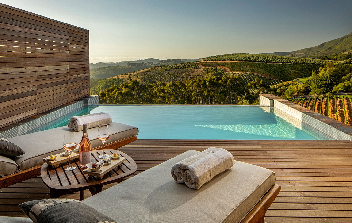 Private lodge plunge pool with timber deck, loungers and vineyard views at Delaire Graff Estate.