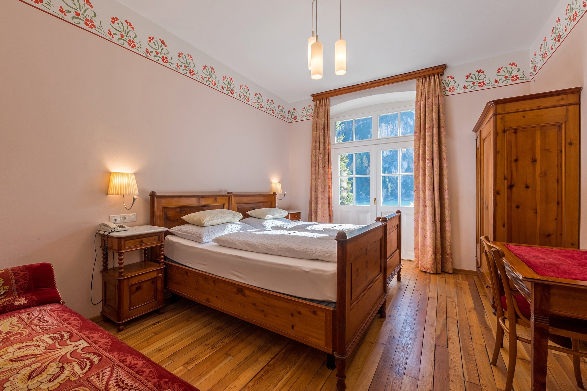Traditional guest room with a wooden double bed at Hotel Lago di Braies, Lago di Braies (Pragser Wildsee), Italy