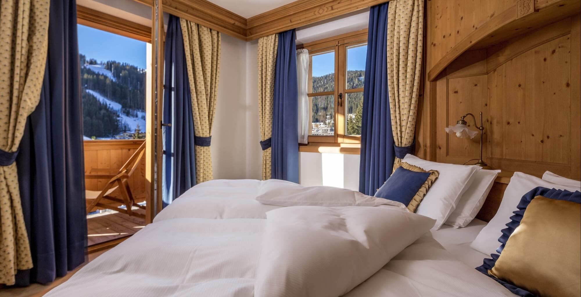 Guest bedroom with wooden finishes and a balcony doorway at Hotel Chalet del Sogno, Madonna di Campiglio, Italy