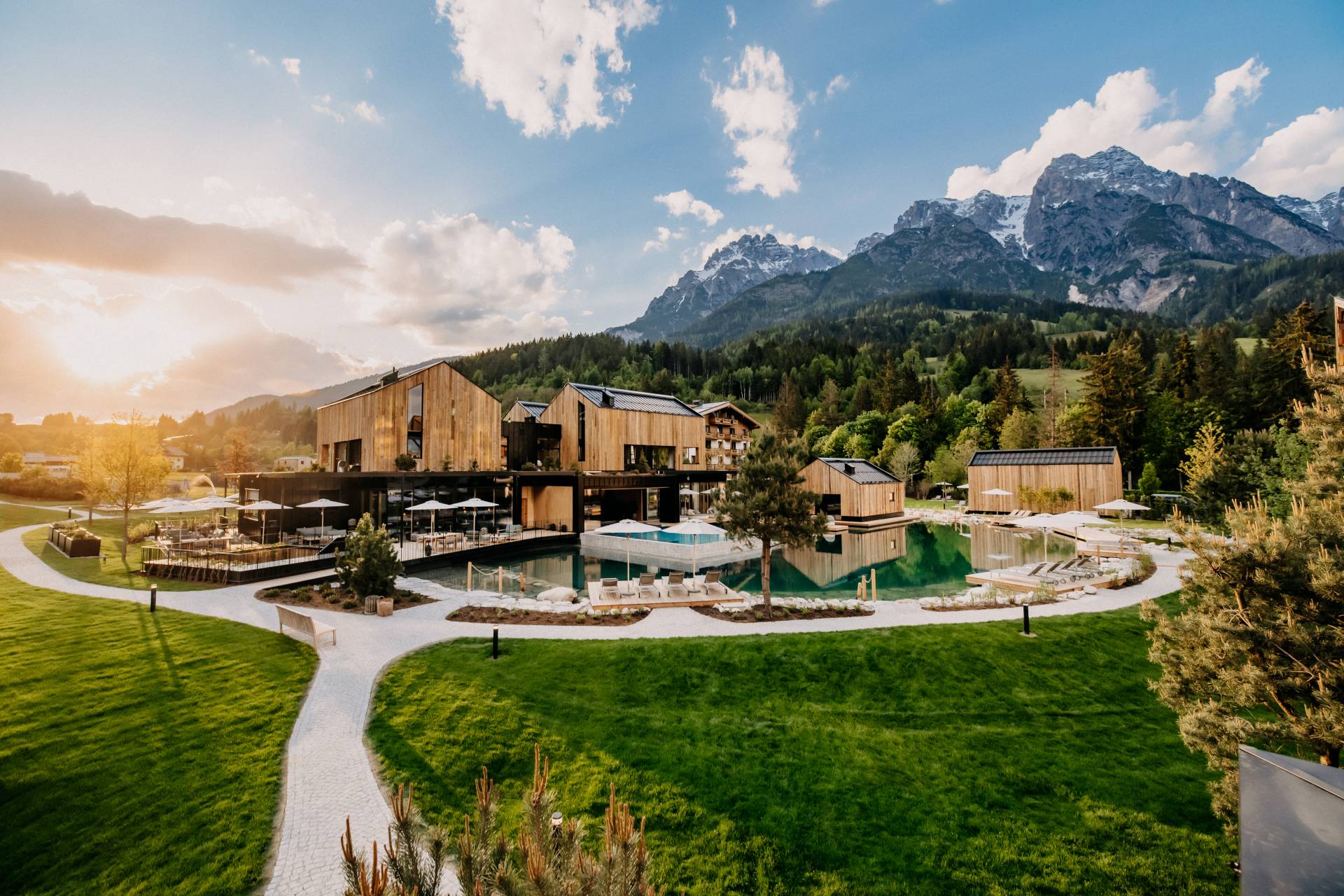 Aerial view of Naturhotel Forsthofgut and its pools and gardens, with the Leogang mountains behind