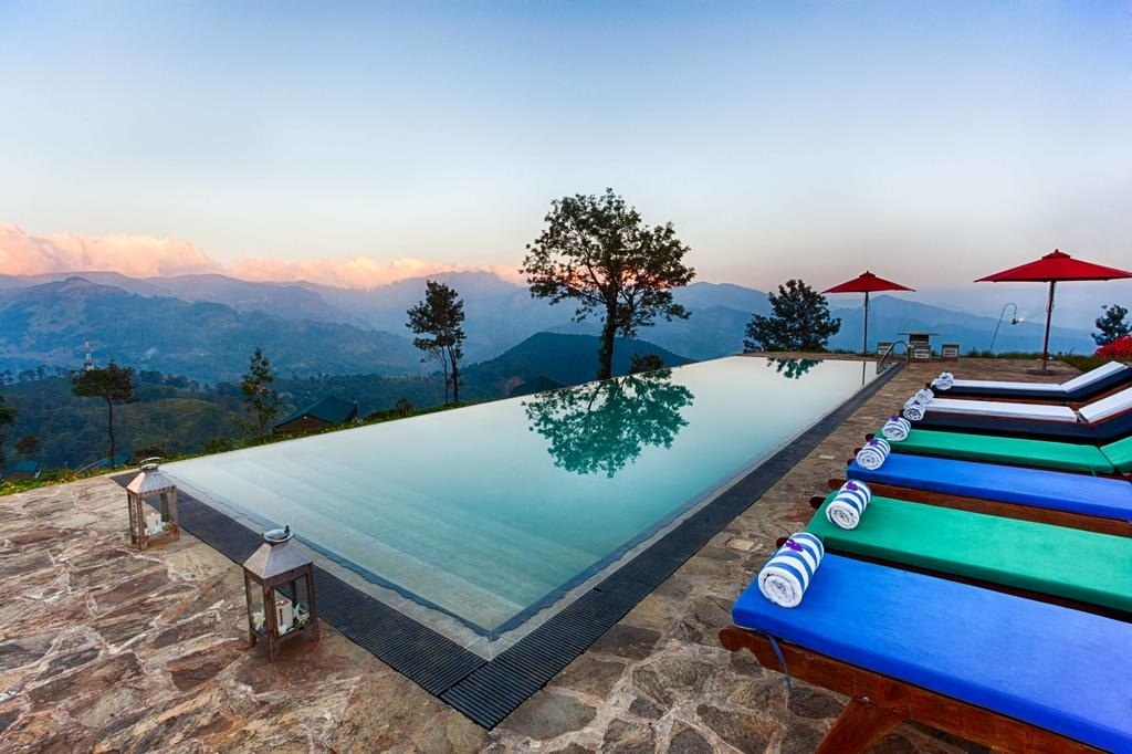 Infinity pool and sun loungers overlooking the mountain valley at dusk