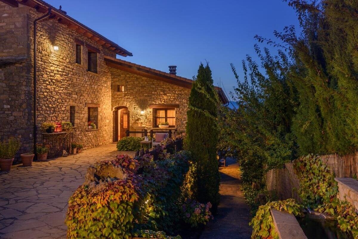 Stone exterior and garden terrace of Hotel Barosse illuminated at dusk, Jaca, Spain
