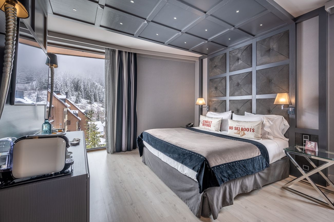 Guest room with a large bed and windows at Hotel Val de Neu, Baqueira-Beret, Spain