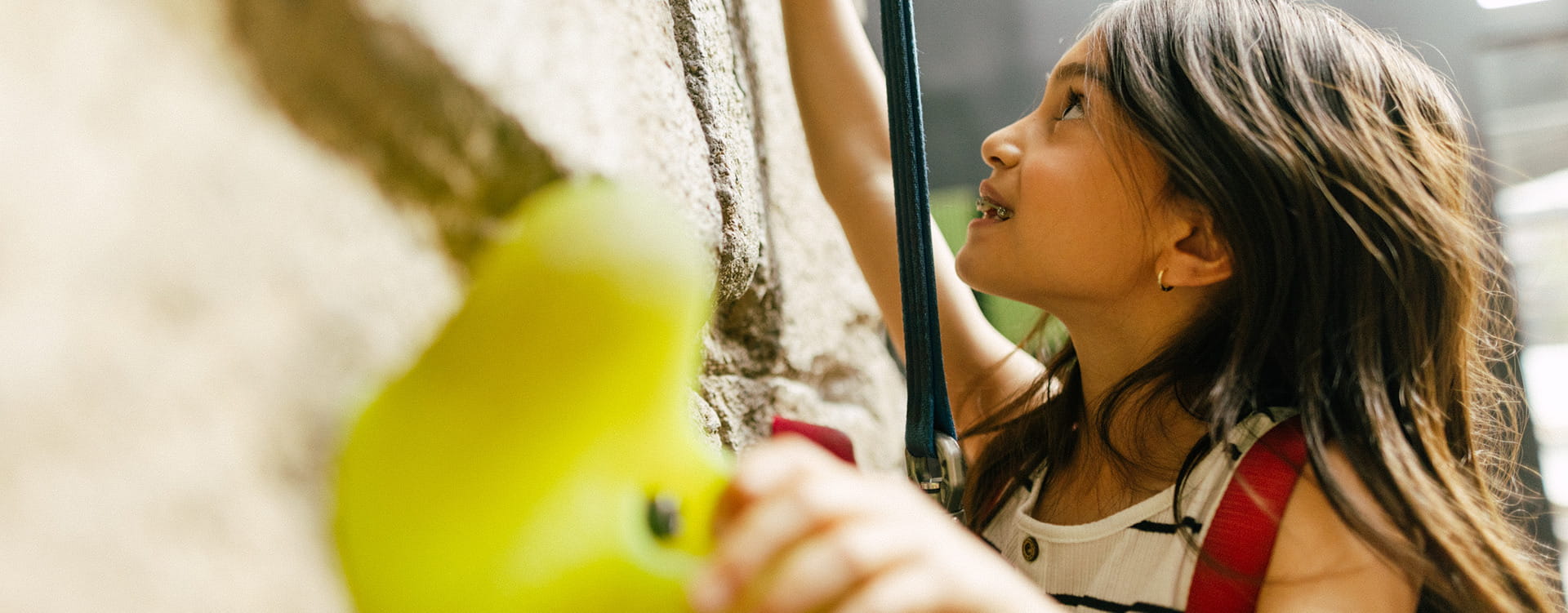 Young climber tackling the rock-style climbing wall at Limelight Hotel Snowmass.