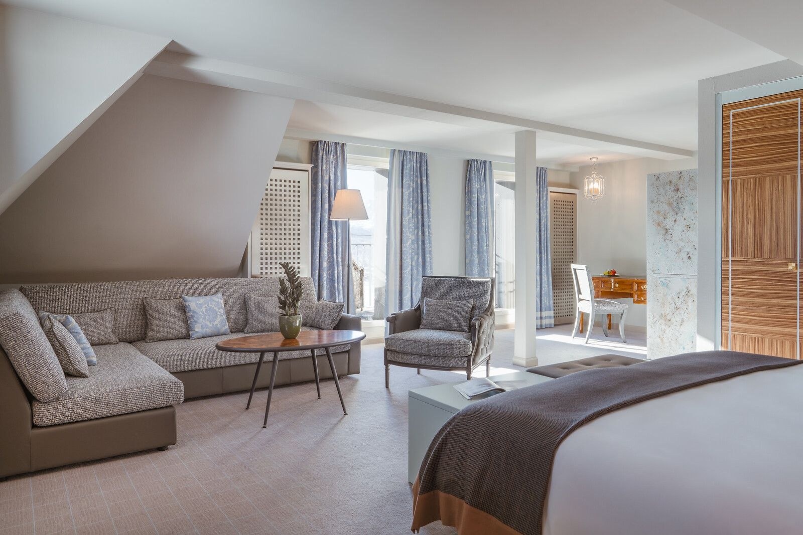 Junior suite bedroom and sitting area with pale sofas and large windows, Carlton Hotel St. Moritz, St. Moritz, Switzerland