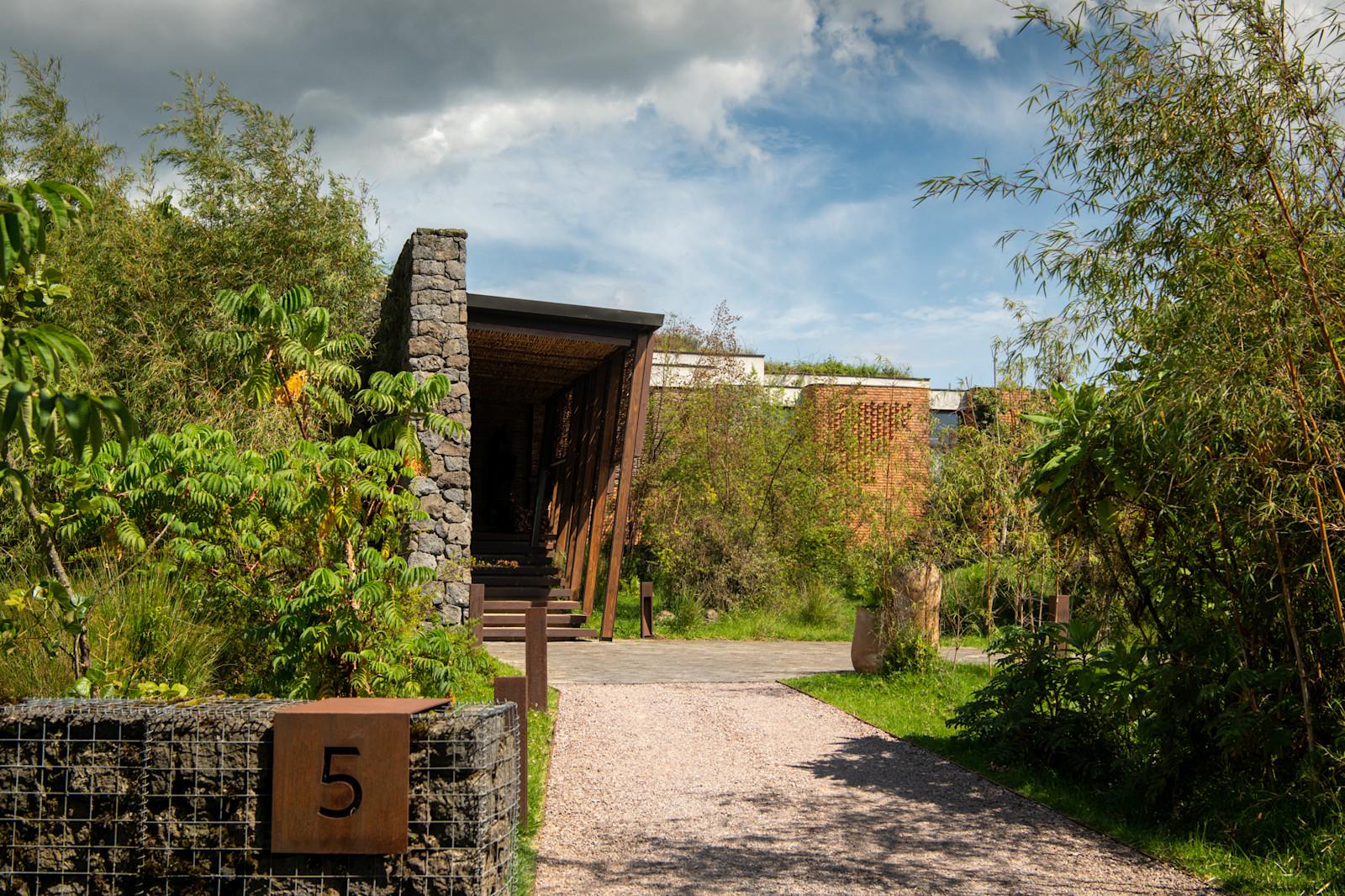 Stone villa exterior and landscaped entrance path, Singita Kwitonda Lodge, Volcanoes National Park, Rwanda