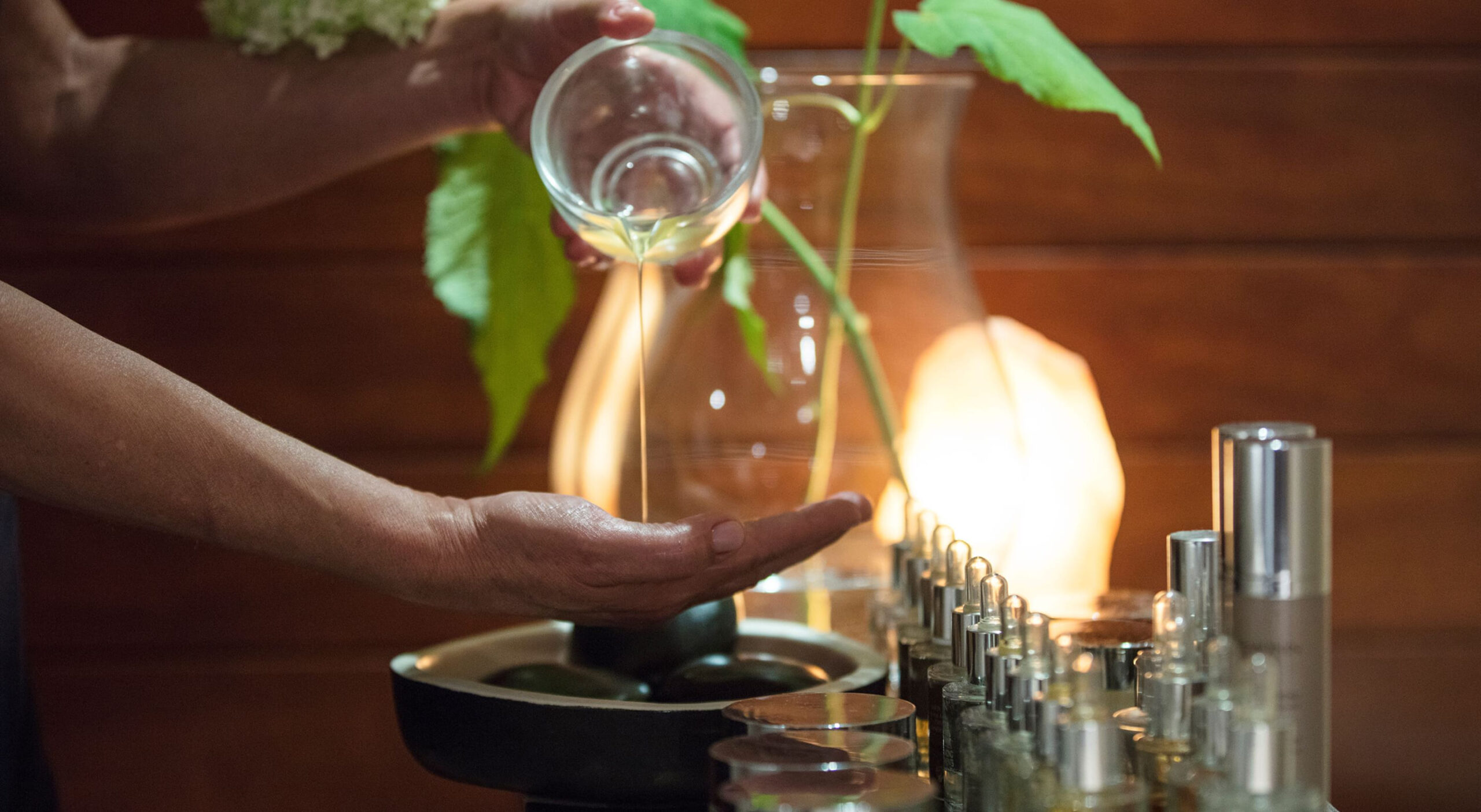 Spa therapist pouring treatment oil beside softly lit bottles, Le Hameau Albert 1er, Chamonix, France