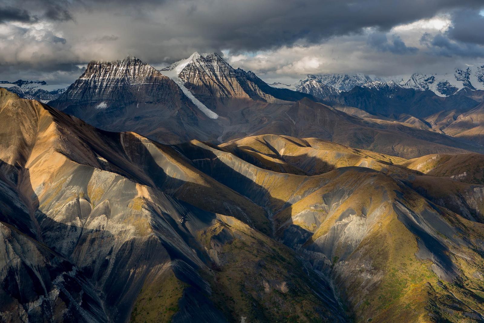 Sunlit mountain ridges beneath dramatic clouds, Ultima Thule Lodge, Alaska, USA