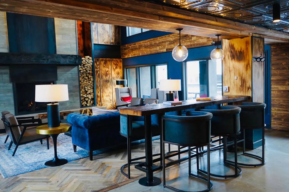 Gravity Haus Breckenridge lobby lounge with blue seating, high tables and a fireplace.