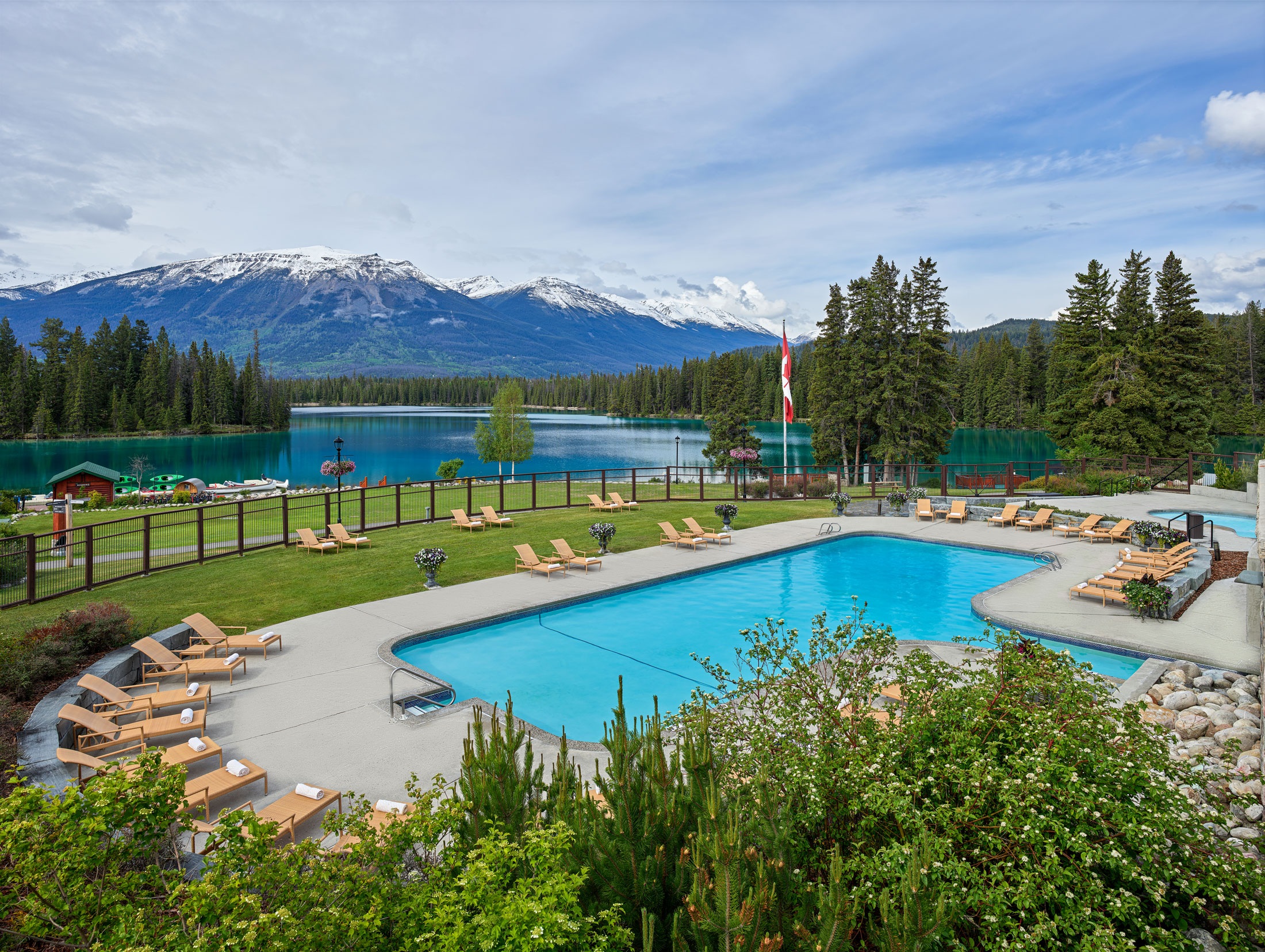 Outdoor swimming pool overlooking lake and distant mountains at Fairmont Jasper Park Lodge, Jasper, Canada