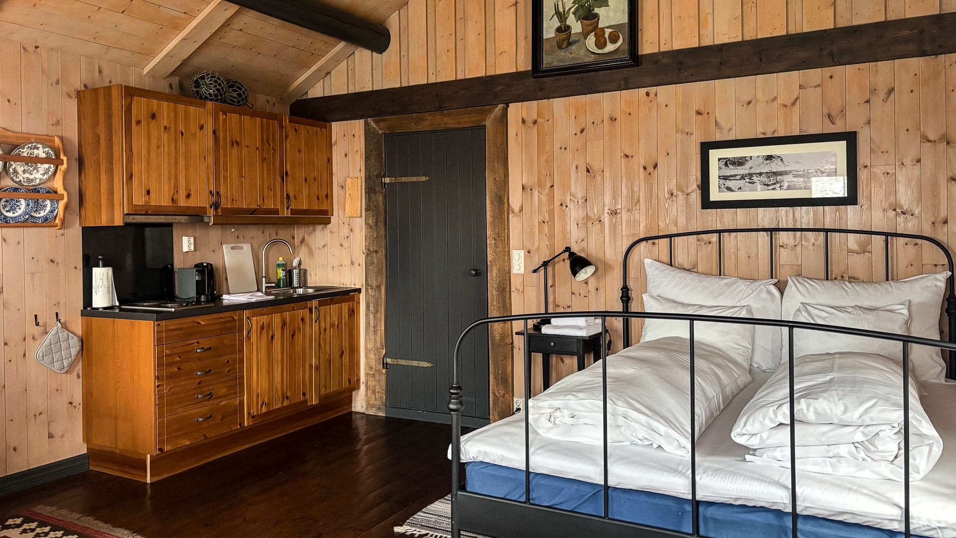 Wood-panelled cabin bedroom with kitchenette at Reine Rorbuer, Reine, Norway