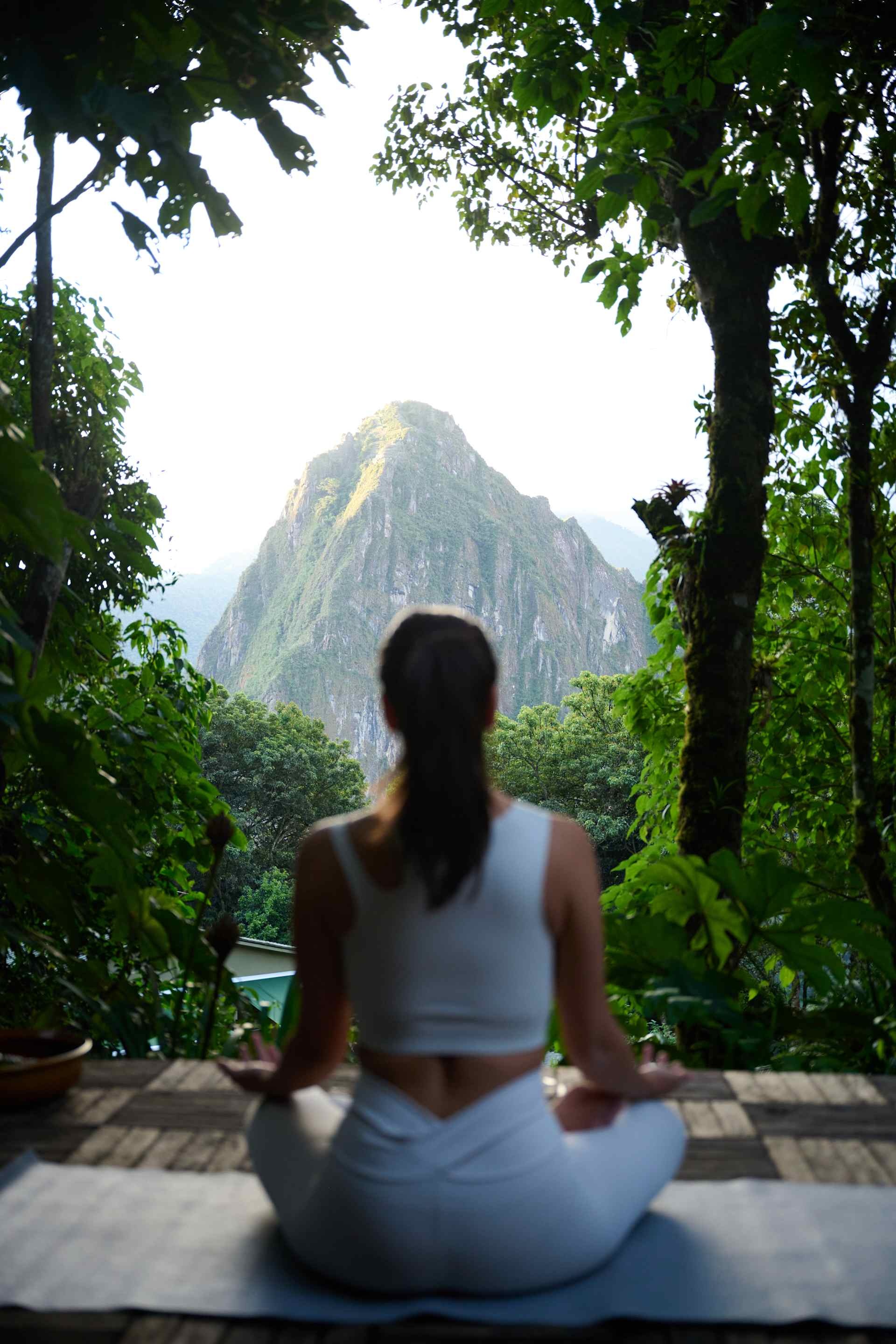 Guest meditating in a garden with a mountain view at Belmond Sanctuary Lodge, Machu Picchu, Peru