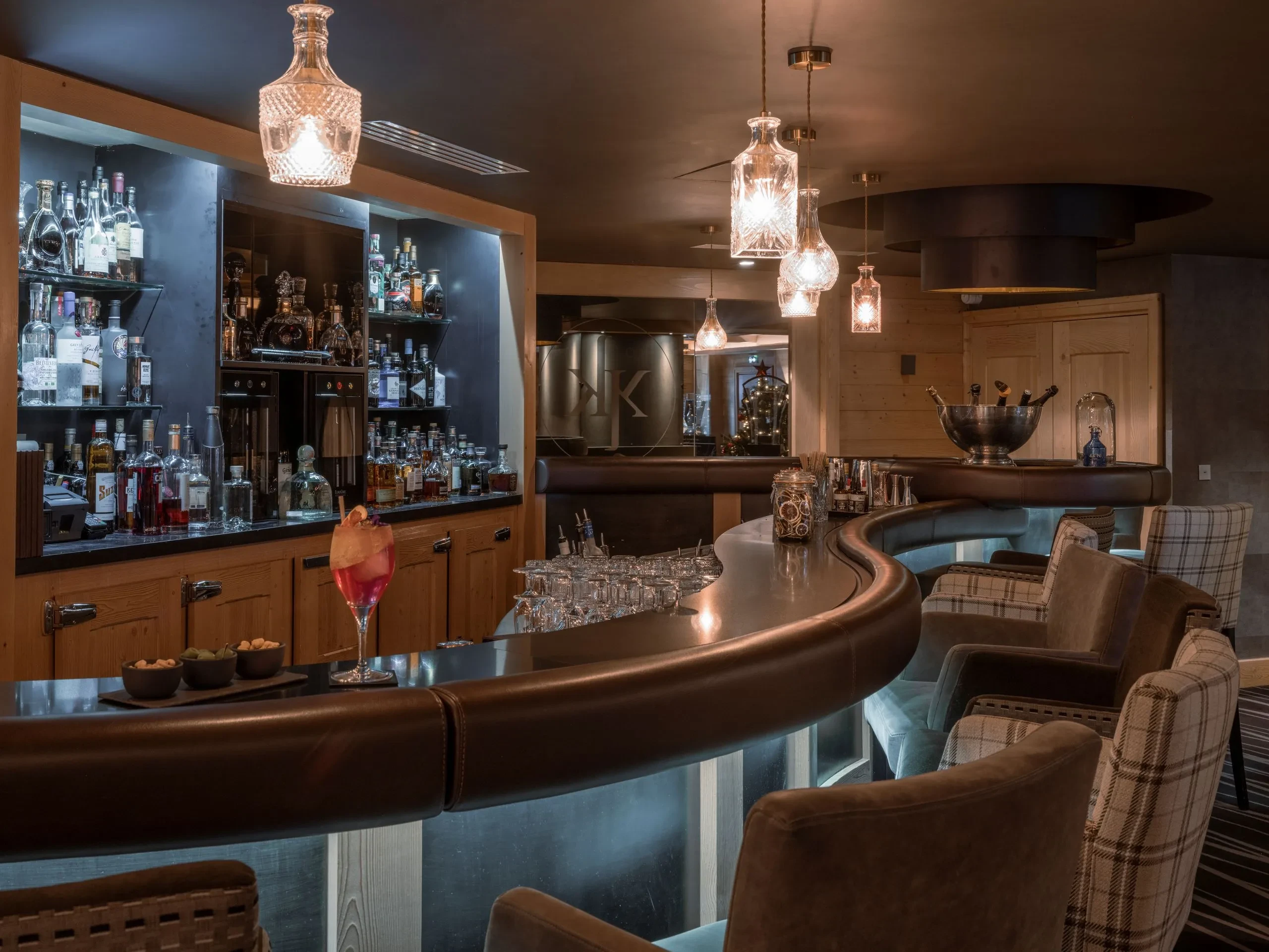 Warmly lit hotel bar with counter seating, Le Kaïla, Méribel, France