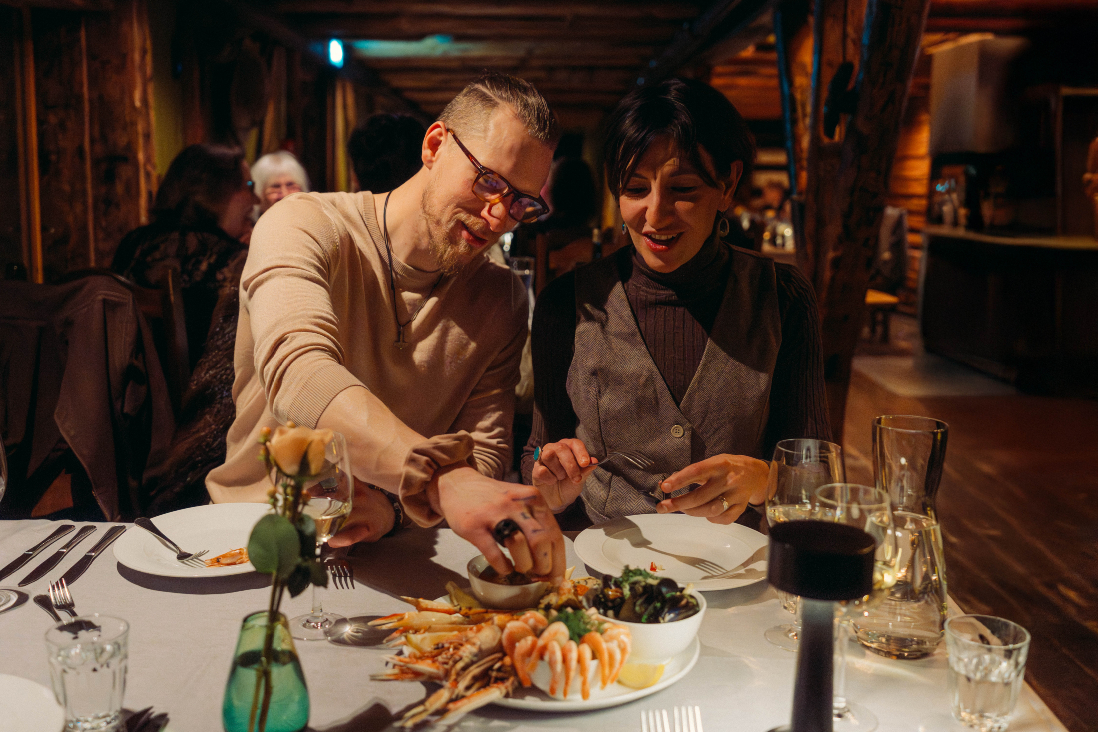 Two guests sharing a meal at a candlelit restaurant table at Svinøya Rorbuer, Lofoten, Norway