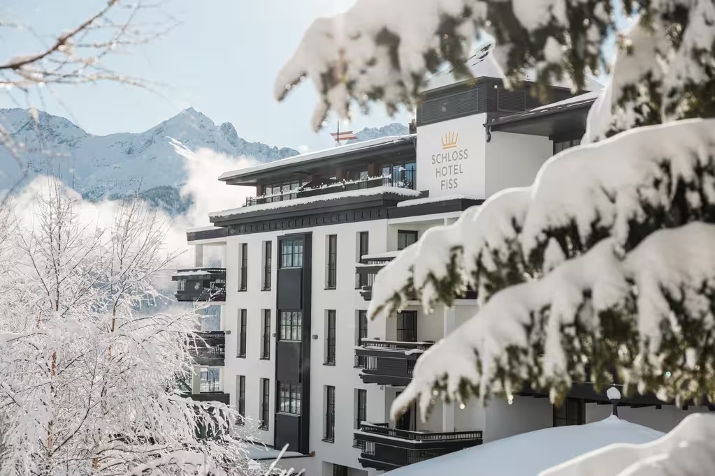 Exterior framed by snow-covered trees and Alpine mountains at Schlosshotel Fiss, Tyrol, Austria