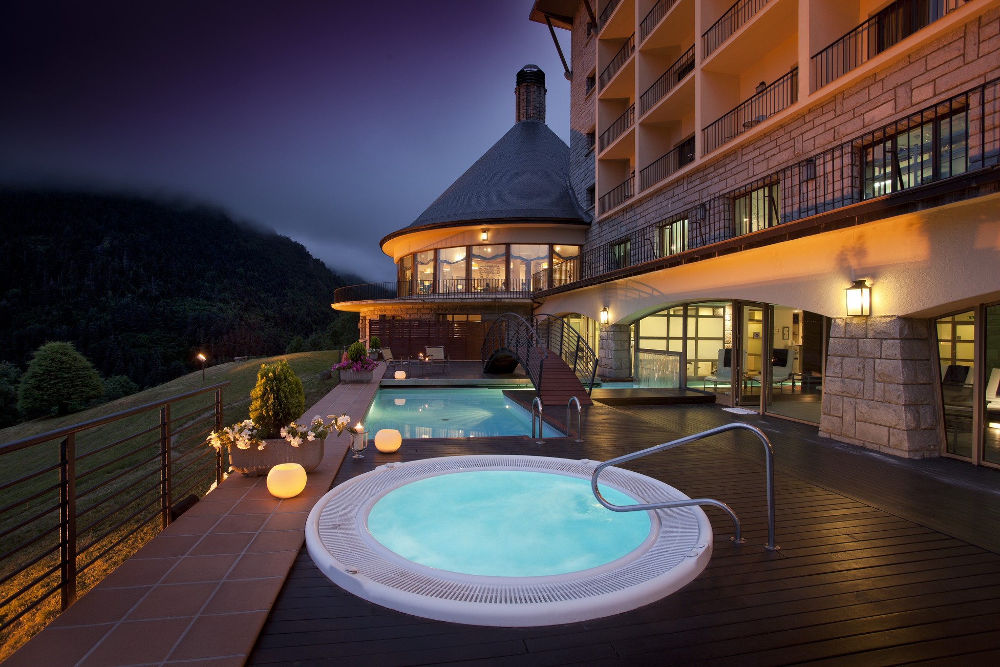 Outdoor whirlpool and illuminated hotel terrace at dusk at Parador de Vielha, Vielha, Spain